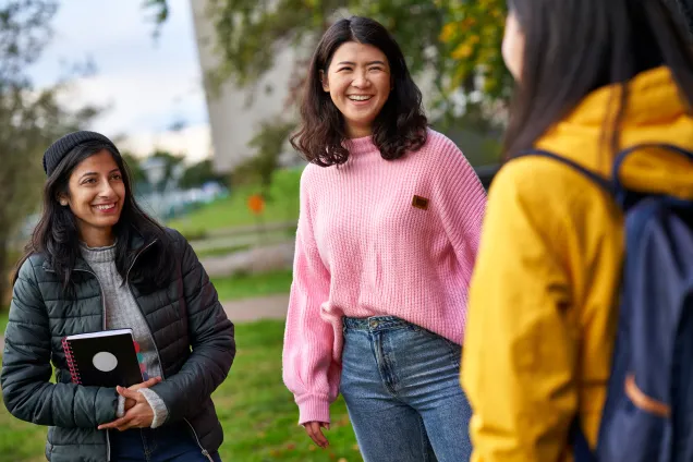 Three students talking and laughing. Photo.
